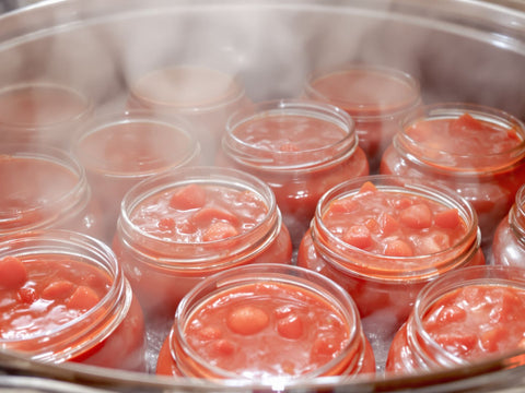 Glass jars filled with vibrant red tomato sauce.