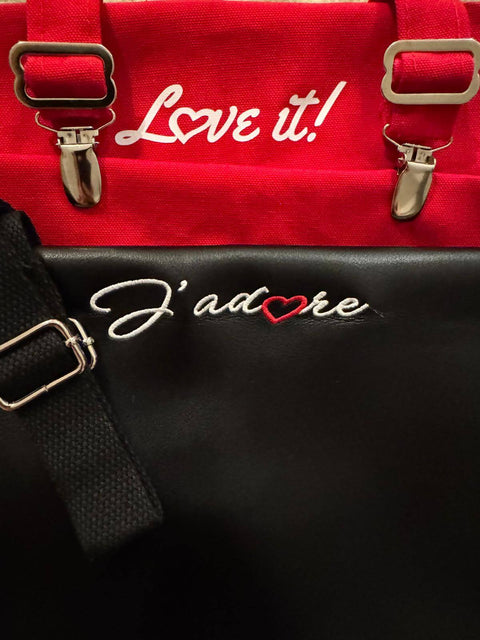 Close-up of J'adore red apron featuring embroidered text 'Love it!' and stylish adjustable straps.