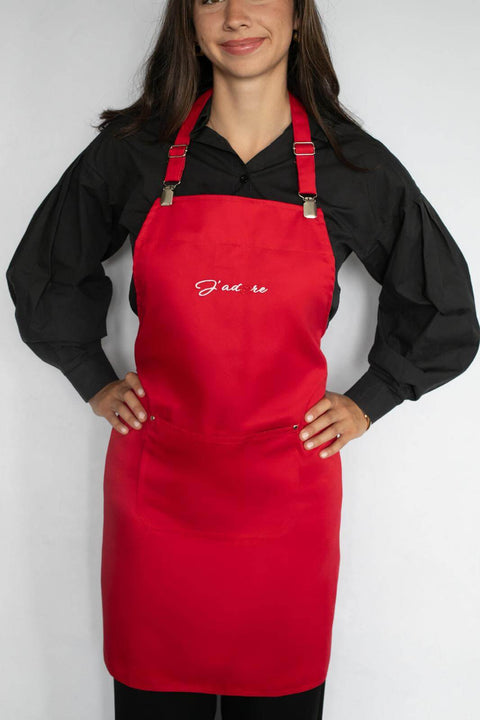 Bold red J'adore cooking apron with adjustable straps and deep pocket, perfect for home chefs in the kitchen.