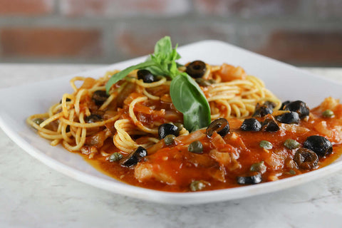 Plate of spaghetti with Gallo Arrabbiata sauce, black olives, and capers, topped with fresh basil.