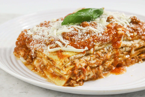 Delicious homemade meat lasagna topped with Gallo Arrabbiata Sauce and basil, served on a white plate.