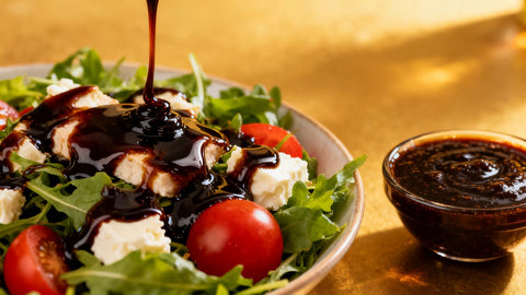Balsamic glaze drizzled over a fresh salad with a bowl nearby.