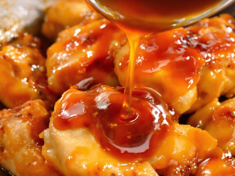 Glossy honey garlic sauce being drizzled over chicken.